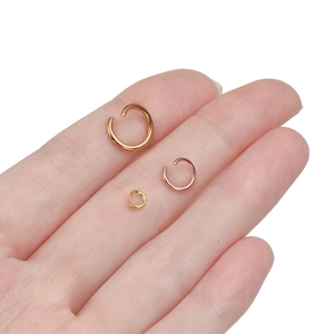 Dettaglio di anellini aperti in oro e oro rosa in tre dimensioni tenuti in mano