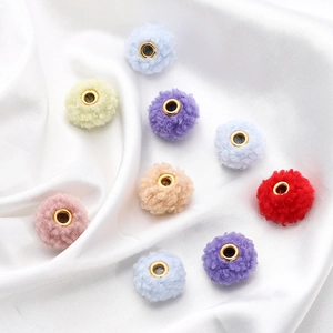 Macro detail of 18mm colorful teddy fleece beads with golden metal eyelets on white silk