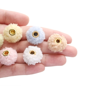 Hand holding 18mm colorful teddy plush beads with metal eyelets for DIY jewelry making