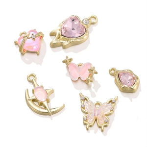 Detail von DIY Herz- und Schmetterlingsanhängern mit rosa Kristallen und Goldmetall
