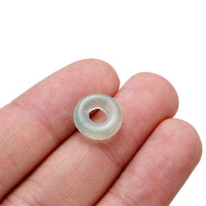 Nahaufnahme einer kleinen minzgrünen Glasperle auf einer Fingerspitze zur Größenansicht