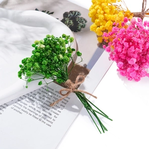 Close-up of mini dried gypsophila bouquets in green, yellow, and pink with jute rope bows