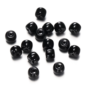 Close-up of polished black cylindrical glass beads with precision holes for DIY jewelry