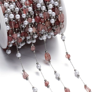 Detail of DIY jewelry chain with white pearls and pink crystal stones on a spool