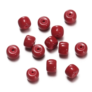Detailed close-up of dark red glass cylinder and disc beads for DIY jewelry making