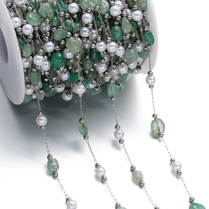 Detail of DIY stainless steel chain with green stones and faux pearls on white spool