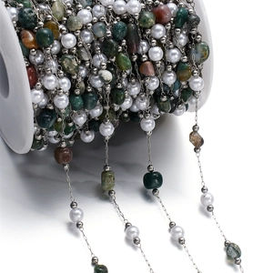 Macro detail of multicolored natural stone beads and pearls on stainless steel chain