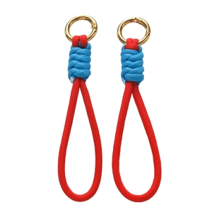 Détail de cordons en paracorde tressée rouge et bleue avec mousquetons ronds dorés