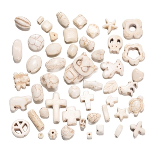 Macro shot of white turquoise DIY beads in owl, skull, and turtle shapes for jewelry making