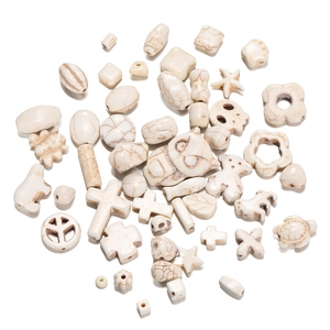 Macro shot of white howlite stone beads in owl, turtle, and heart shapes for DIY jewelry