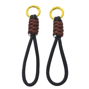 Détail de cordons en paracorde tressée avec anneaux métalliques jaunes et nœuds bruns