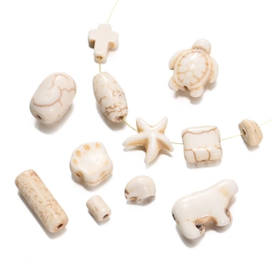 Macro shot of assorted white turquoise beads in cross, turtle, and starfish shapes for DIY