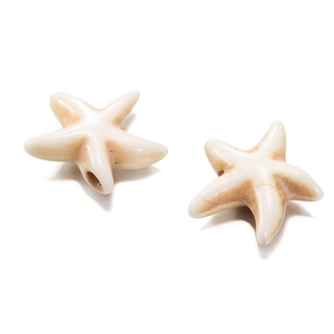 Detail view of two white starfish-shaped synthetic stone beads with brown antique texture