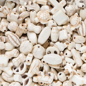 Macro view of white turquoise beads in star, cross, and turtle shapes for DIY jewelry