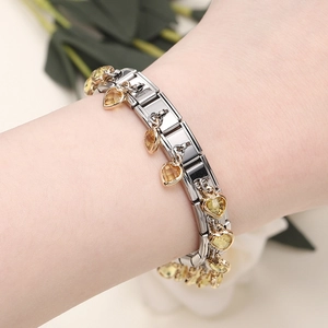 Close-up of heart-shaped yellow gemstone charms on a modular stainless steel bracelet