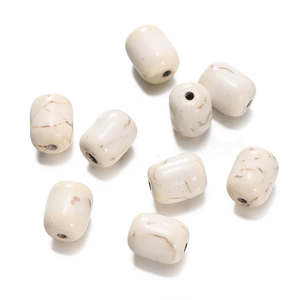 Macro detail of barrel-shaped white turquoise beads with brown marble texture and pre-drilled holes
