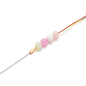 Macro detail of stainless steel beading needle threading colorful round beads for DIY