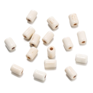 Macro shot of white synthetic turquoise cylinder beads with natural brown veins and drill holes