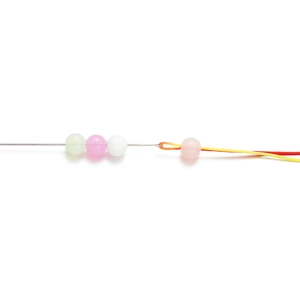 Detailed macro of stainless steel beading needle threading translucent DIY jewelry beads