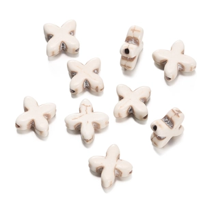 Macro shot of cross-shaped white turquoise beads with natural marble textures for DIY jewelry