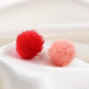 Macro detail of red and pink faux fur pompom beads on elegant white silk background