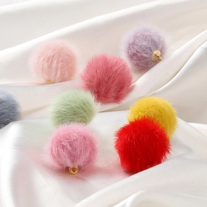 Macro shot of colorful plush mink fur pompom charms with gold metal loops for DIY jewelry