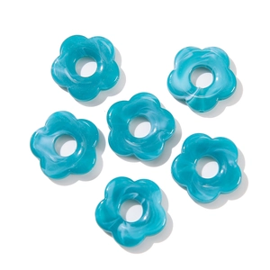 Macro detail of six blue marble-textured acrylic flower beads with center holes