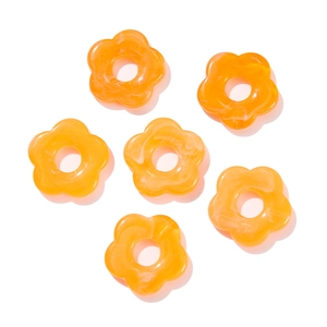 Macro detail of 26mm acrylic flower beads with orange marble texture and center holes