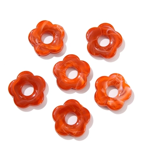 Macro shot of 6 orange acrylic flower beads with white marble texture for DIY jewelry