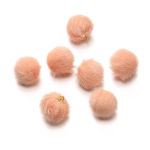 Close-up of pink faux mink fur ball pendants with gold metal rings for DIY jewelry