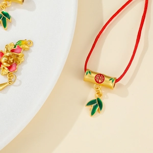 Detailed close-up of golden bamboo pendant with red Fu character and green enamel leaf