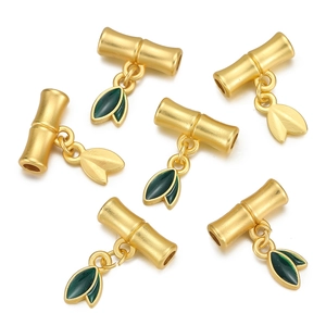 Detailed view of handmade gold bamboo leaf pendants with green enamel for DIY jewelry