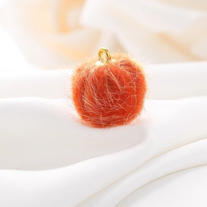 Macro-opname van een 15mm oranje pluche bolhanger met een gouden metalen lus