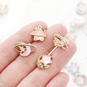 Detailed macro view of gold-plated star and moon alloy charms with pink rhinestones