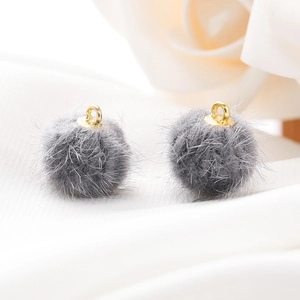 Detailopname van grijze imitatiebont pompon hangers met gouden ringen voor DIY sieraden