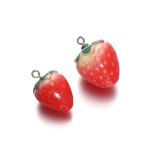 Close-up of resin strawberry charms with red gradient finish and metal rings for DIY