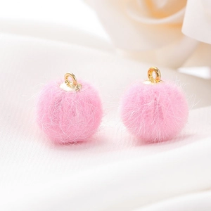 Detail van felle roze imitatiebont pompons met gouden oogjes voor DIY sieraden maken