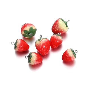 Macro detail of resin strawberry charms with silver jump rings for DIY jewelry making