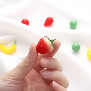 Close-up of mini resin strawberry charm for DIY jewelry being held to show small scale