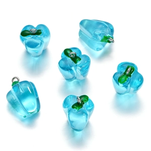 Macro detail of sky blue glass pepper charms with green stems and metal loops for DIY jewelry