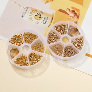 Detalle de varios accesorios dorados para joyería en una caja organizadora de plástico