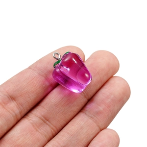 Detailed macro view of a translucent strawberry charm pendant resting on a palm