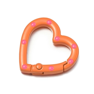 Nahaufnahme eines orangefarbenen Herz-Karabinerverschlusses mit rosa Punkten für DIY-Schmuck