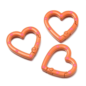 Detail von herzförmigen Karabinern in Orange mit rosa Punkten für DIY-Schmuck