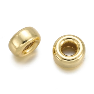 Detail of two golden polished large hole spacer beads for DIY jewelry making