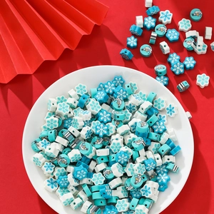 Nahaufnahme von blauen Schneeflockenperlen und Schneemann-Tonperlen für DIY-Schmuck