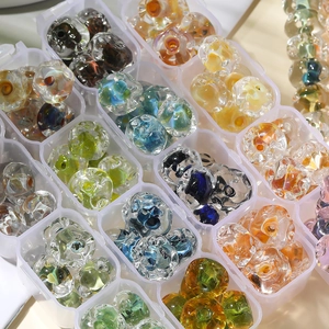 Macro di perline di vetro colorate da 12 mm organizzate in una scatola di plastica a griglia