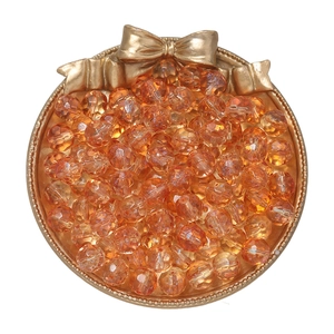 Macro view of 10mm faceted amber glass beads in a golden tray for DIY jewelry