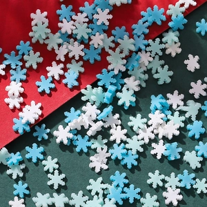 Makroaufnahme bunter Schneeflocken-Polymer-Perlen vor festlichem rot-grünem Hintergrund