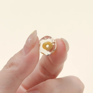 Dettaglio macro di perla di vetro irregolare da 12mm con cuore giallo e facce lucide